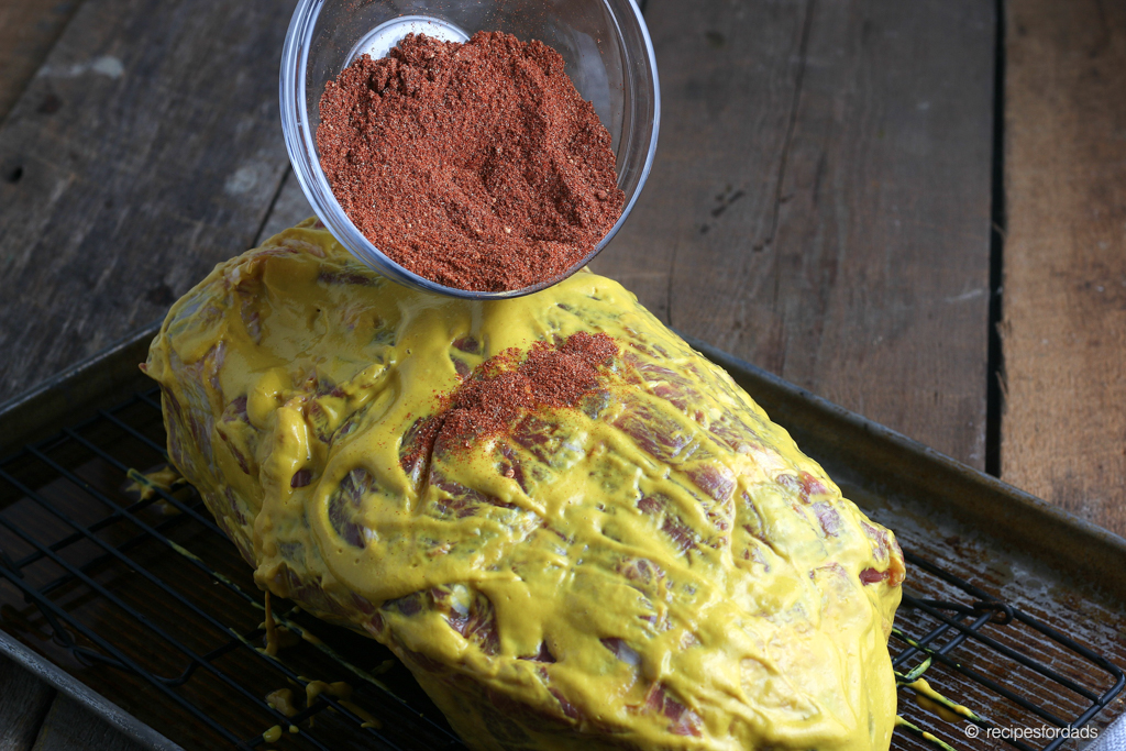 Pouring some Cayenne pepper on top of smoke pork shoulder