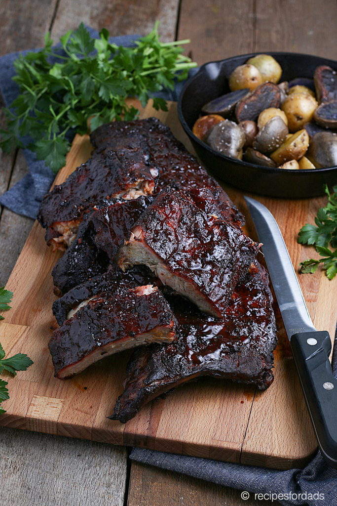 smoked baby back ribs on cutting board served with potatoes