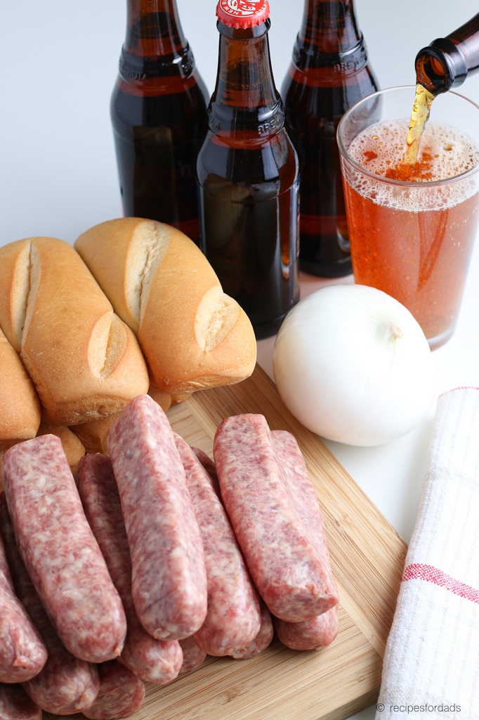 Beer, Hoagie buns, uncooked brats and onion served on cutting board