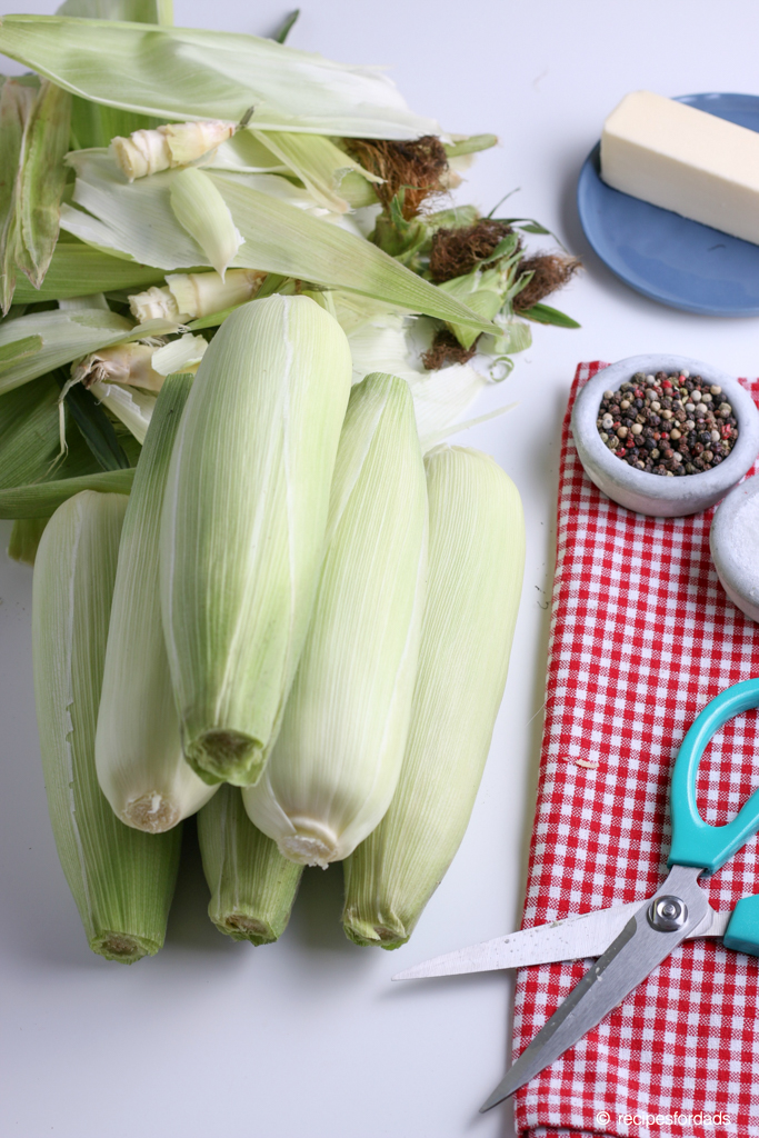 Trimming silk and removing stalk on the corn on the cob using scissors