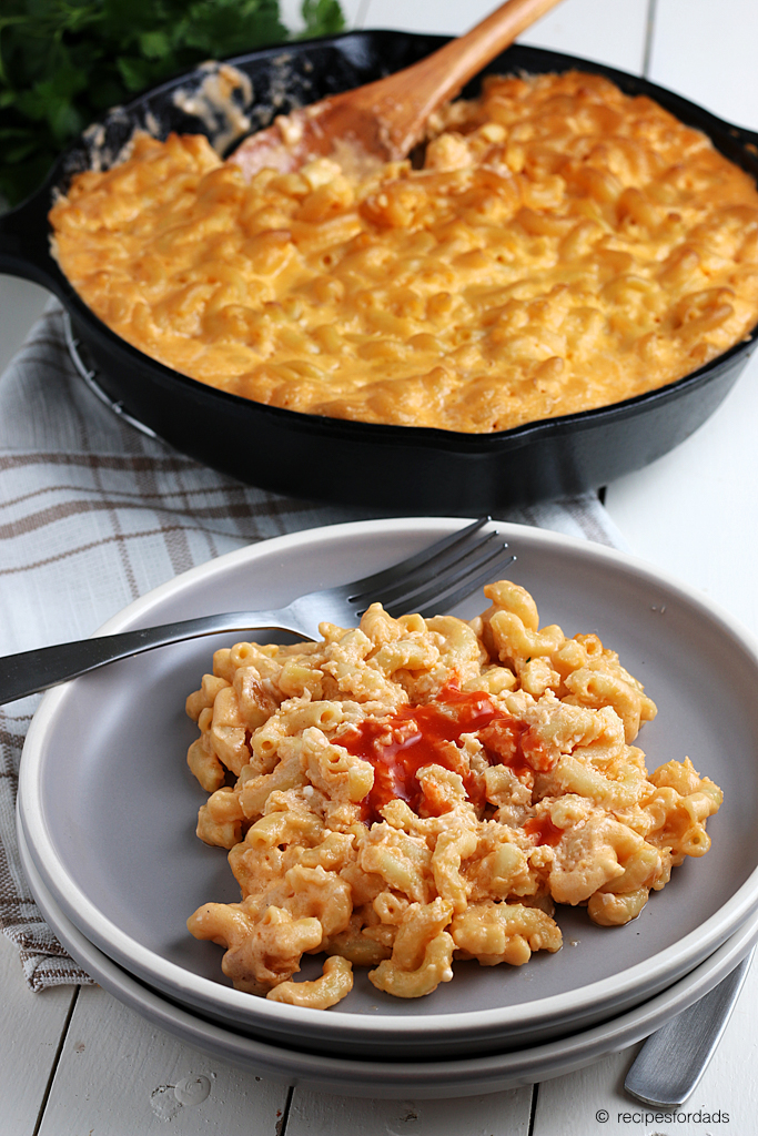 Smoked mac and cheese in a cast iron skillet served with hot sauce on top
