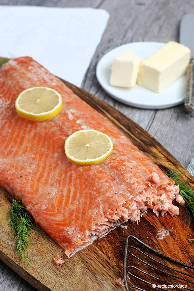 Smoked salmon served with butter and lemon wedges, served on brown serving platter