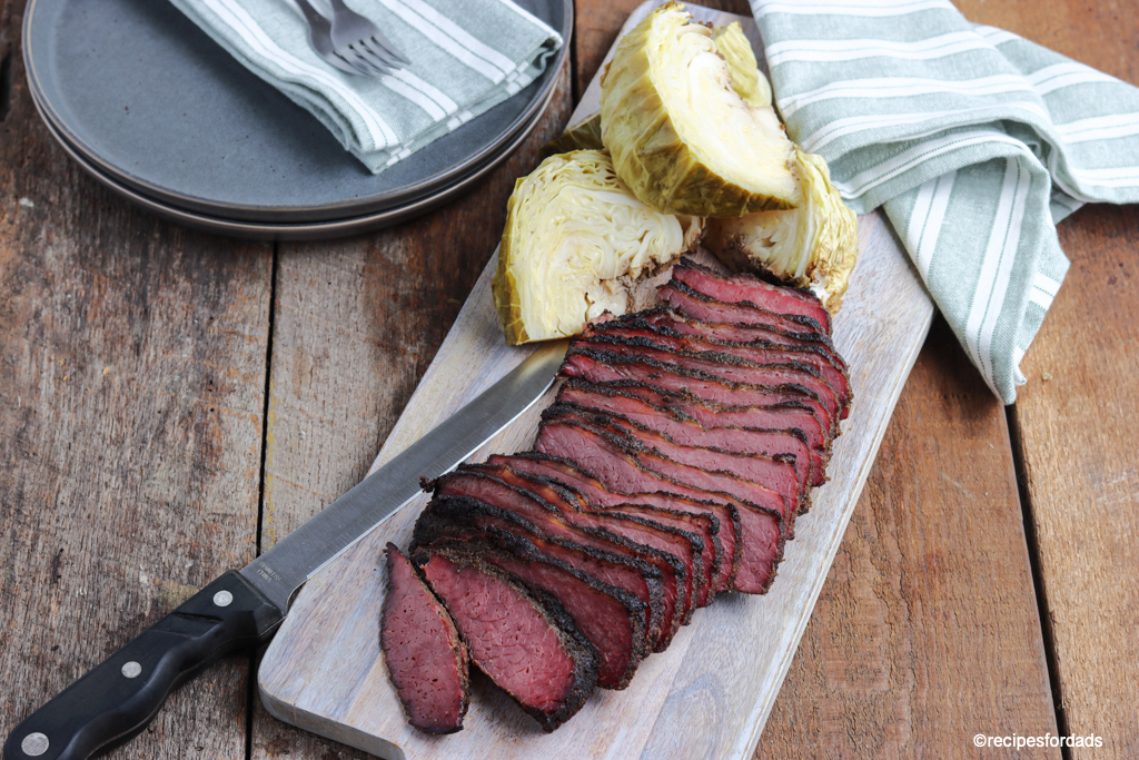 sliced brisket and sliced cabbage served on cutting board