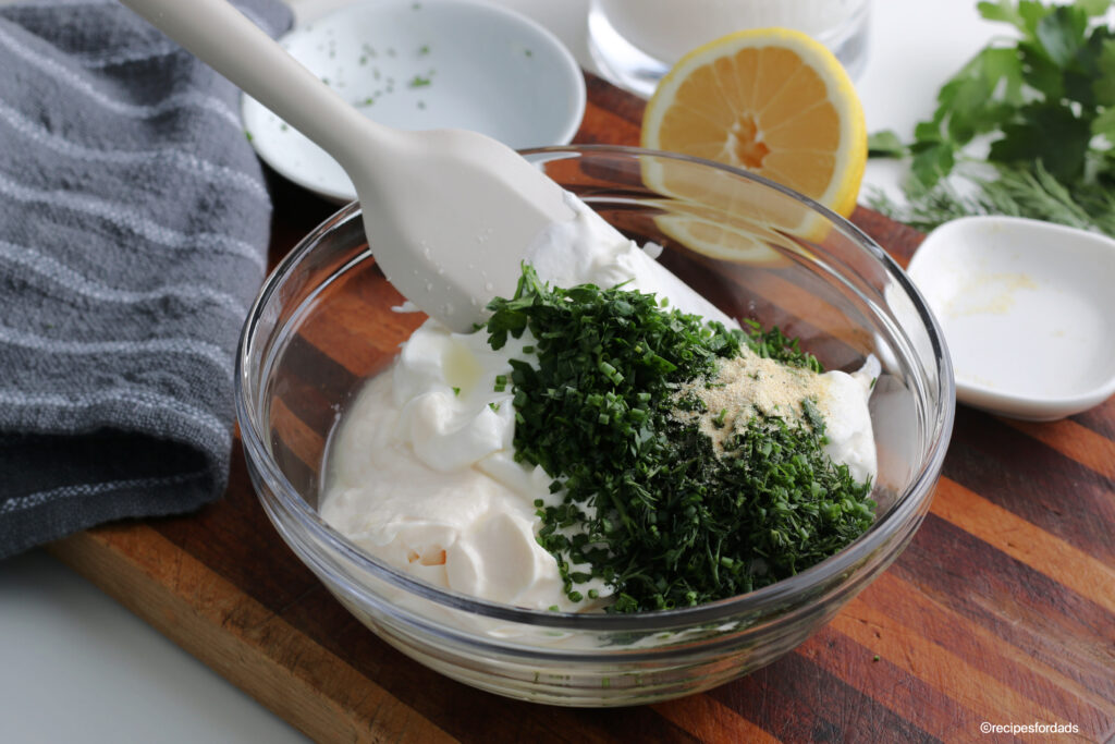 mixing ingredients together to make homemade ranch dressing, displayed on wood board 