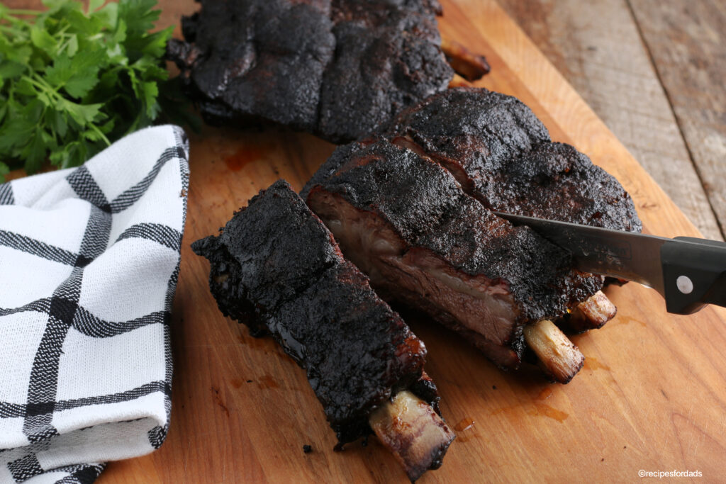 Cutting beef ribs on cutting board with knife and black & white napkin