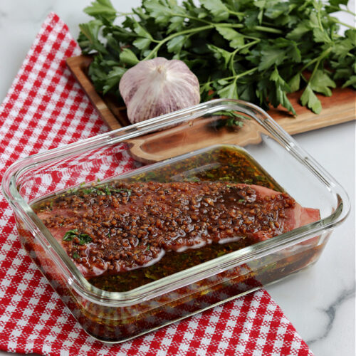 steak marinating in glass dish