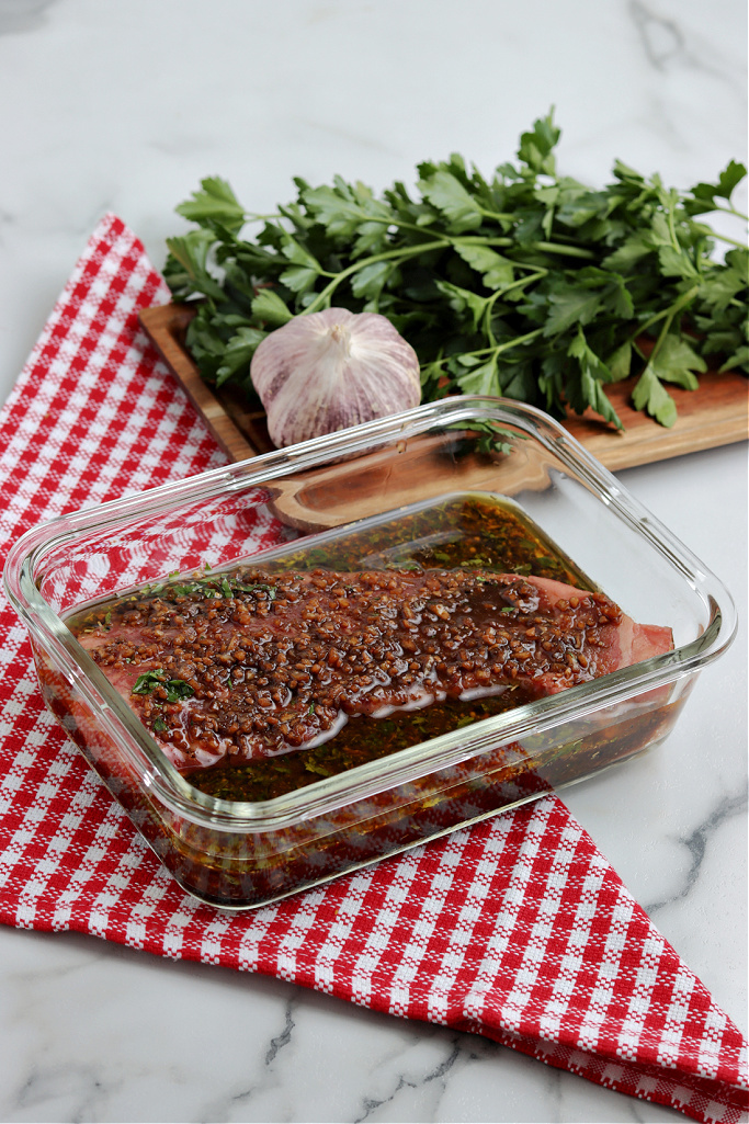 steak marinating in glass dish