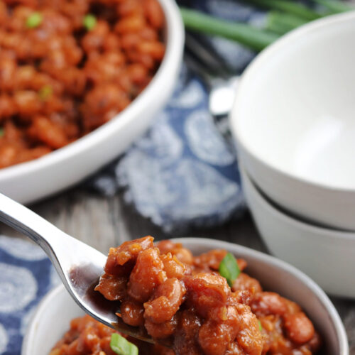 baked beans served in white bowl, with pressure cooker in the background