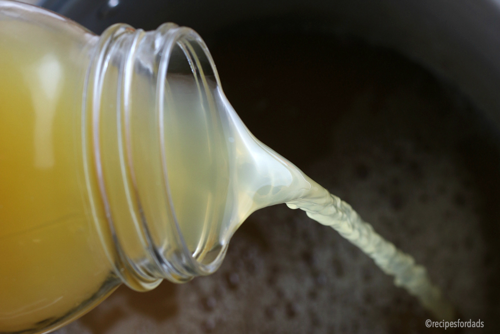 pouring chicken stock into pan