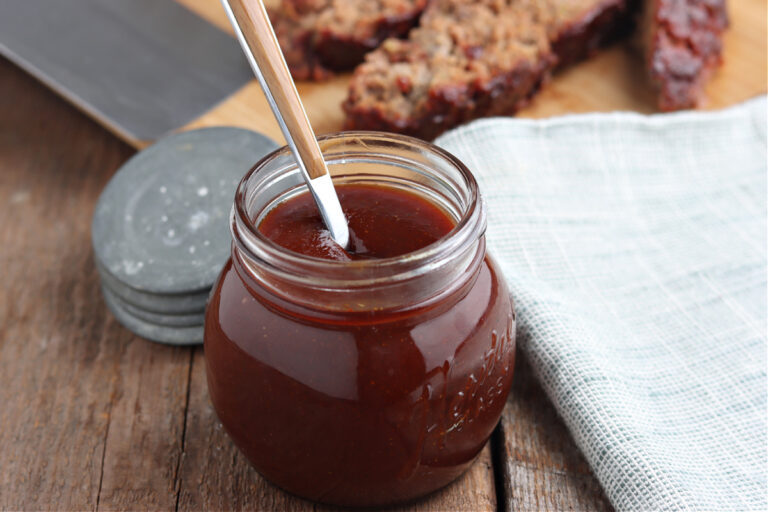 BBQ sauce in glass jar with meatloaf on board