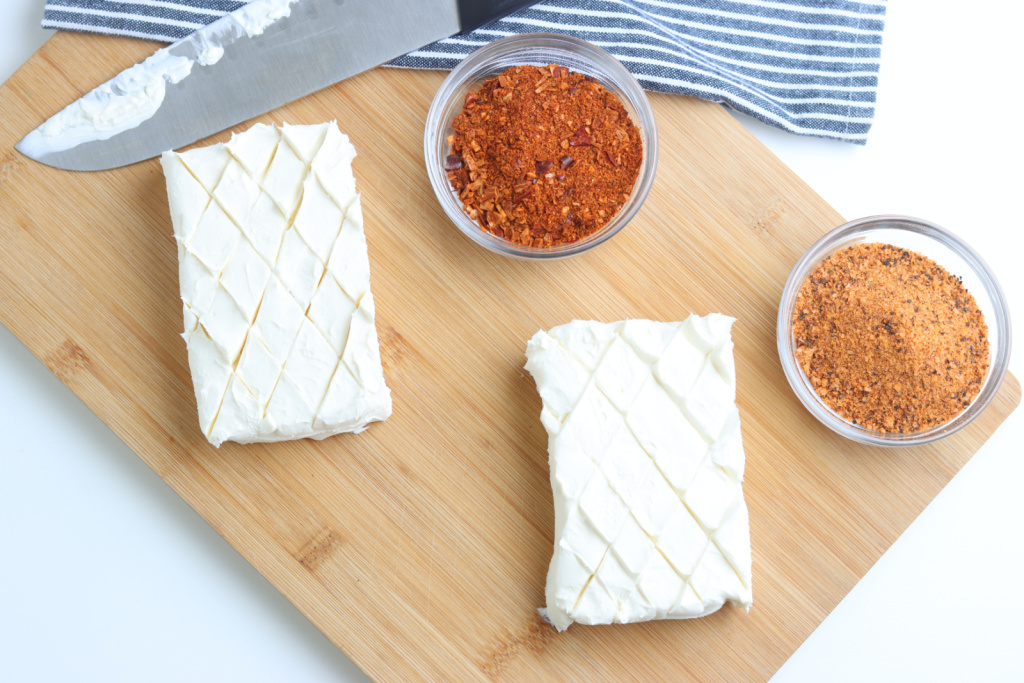 cream cheese scored with a knife and seasoning blends in glass bowls