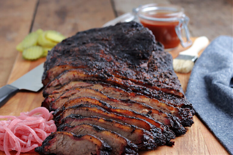smoked brisket sliced on cutting board with barbecue sauce
