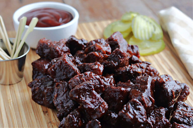 smoked pork belly ends on cutting board with barbecue sauce and pickles