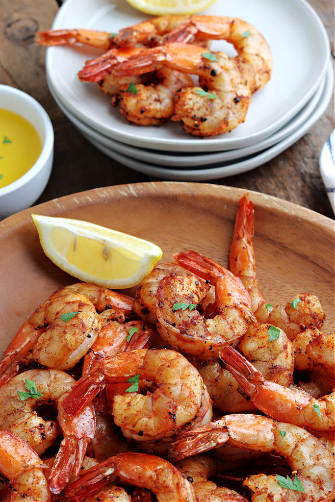 smoked shrimp in wood bowl with parsley and lemon wedges and on plate