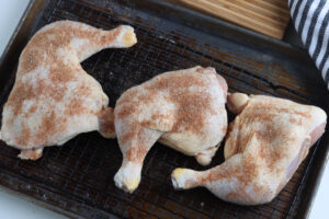 chicken quarters seasoned on wire rack