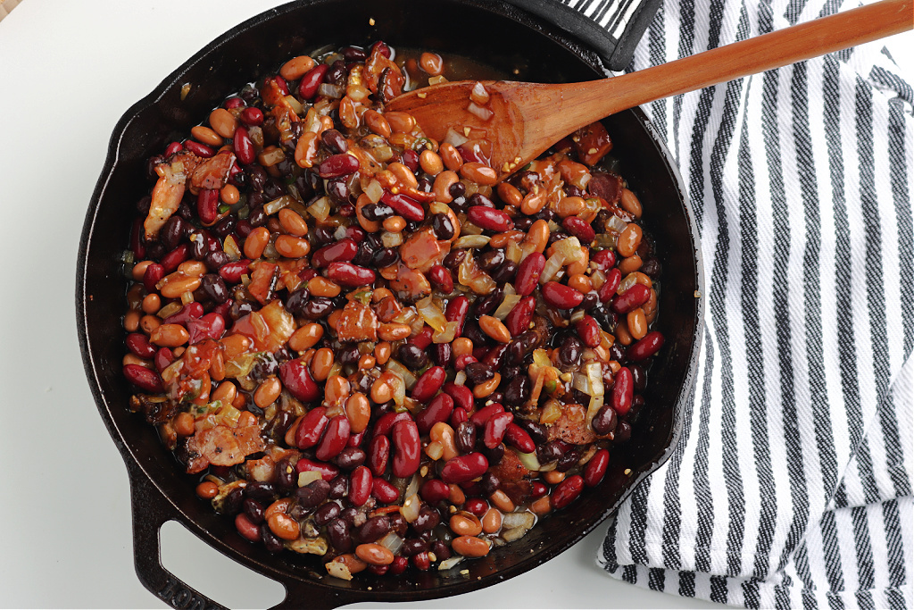 beans, bacon, and seasoning mixed in cast iron skillet
