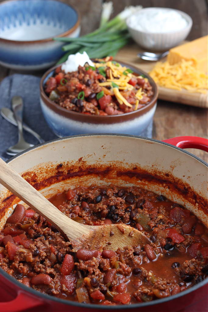 smoked chili in bowl with cheese, green onions and sour cream