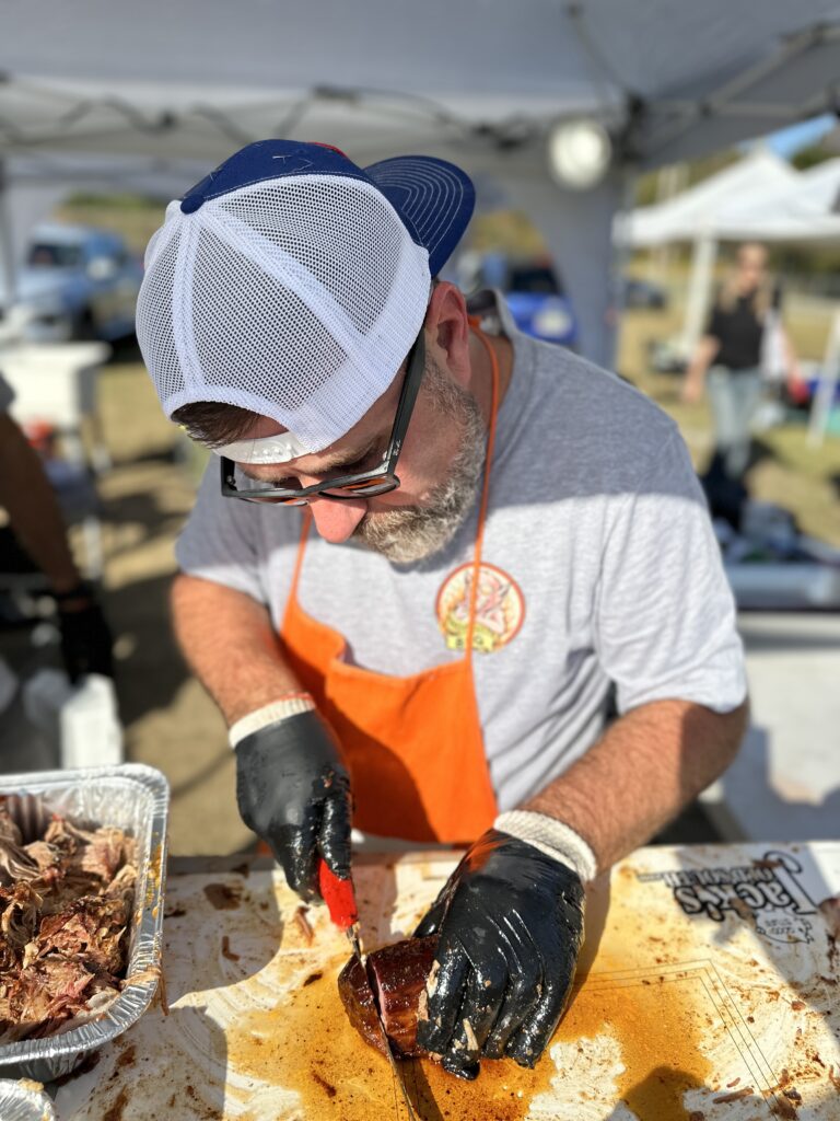 Mark Rogers from Pit Nation BBQ cutting money muscle out of a pork shoulder at a bbq competition